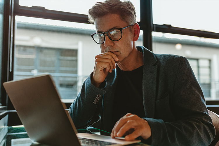 homem de óculos analisa informações em seu notebook