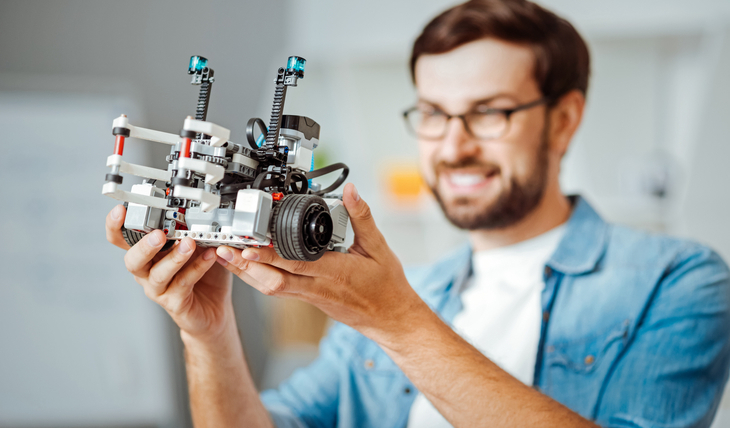 Homem sorrindo e vendo um robo ilustrando robos na área de investimento