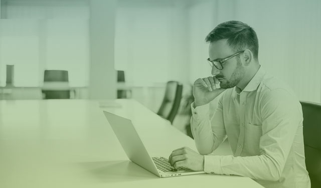 Homem de camisa social utilizando computador