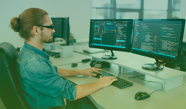 Homem programando códigos em duas telas de computador