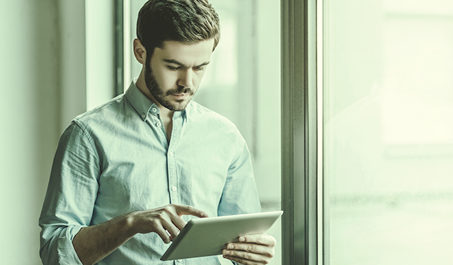 Homem de camisa social mexendo em tablet