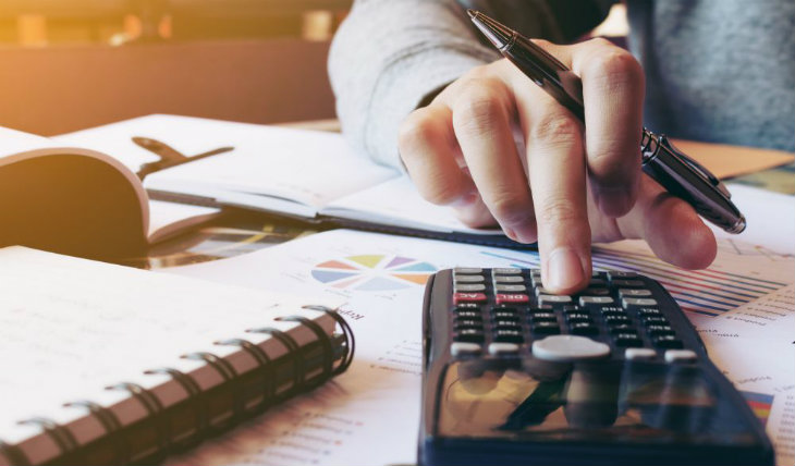 Homem em mesa de escritório utilizando calculadora