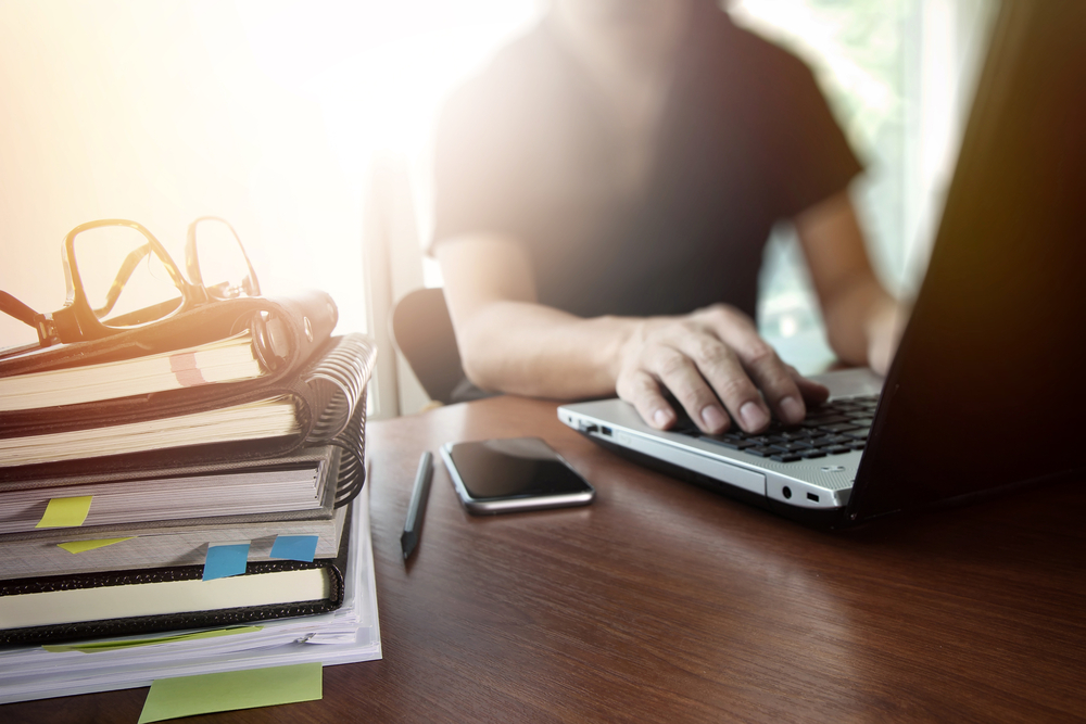 Pessoa trabalhando em um laptop em uma mesa com livros