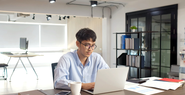 Homem numa sala de escritório utilizando o computador