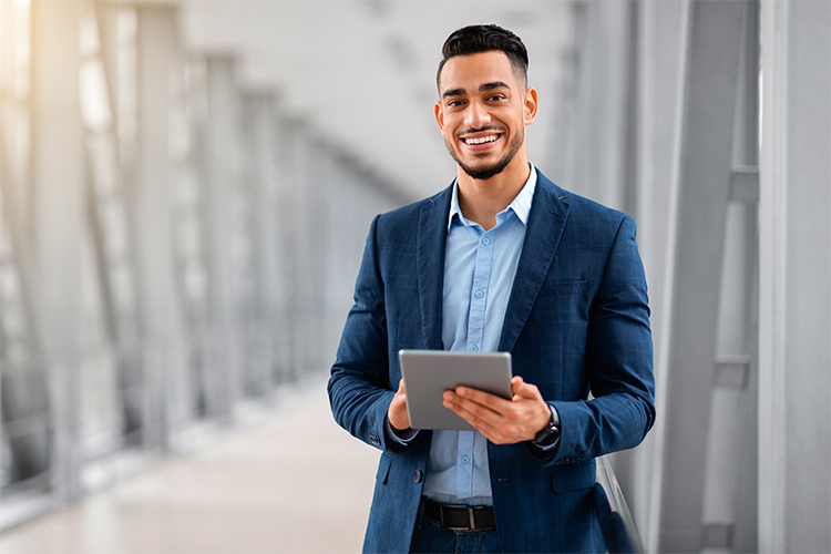 Homem vestido de terno utilizando um tablet e sorrindo