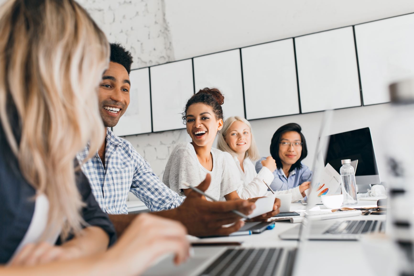 Cinco pessoas felizes em uma sala de reunião