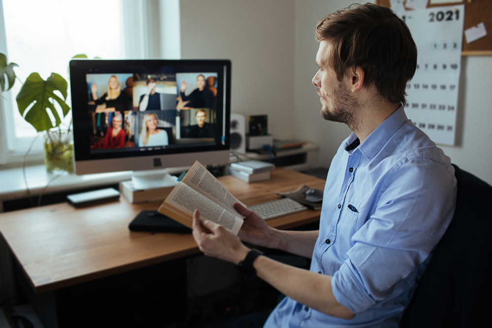 Homem com livro na mão numa reunião online