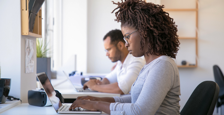 Pessoas sentadas em um escritório trabalhando no notebook