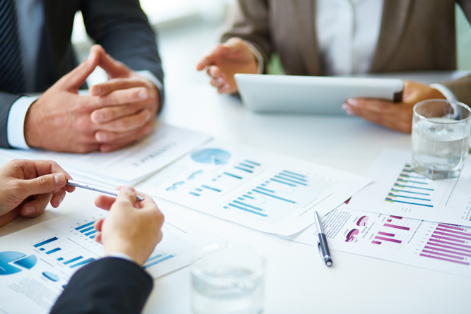 Pessoas em uma mesa de reunião analisando gráficos