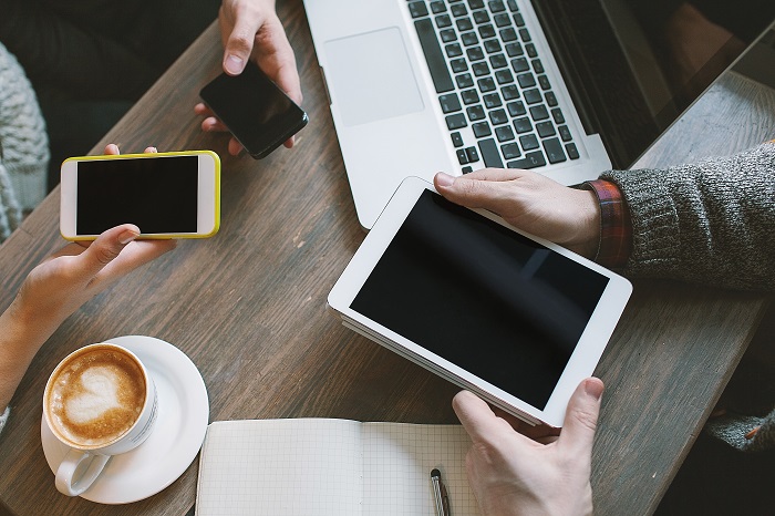 Pessoas utilizando celular e tablet em um café